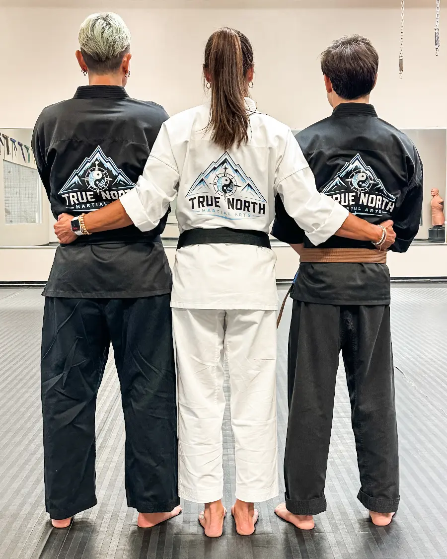 Three instructors wearing uniforms printed with the True North Martial Arts logo